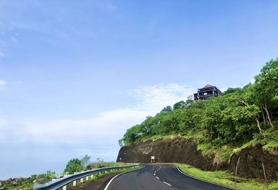 Road amidst trees against sky