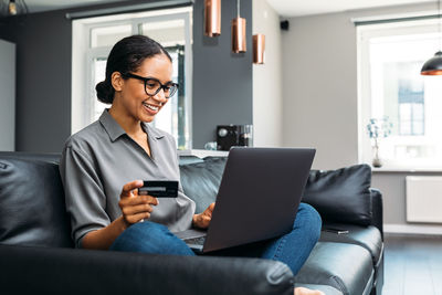 Woman doing online shopping while sitting on sofa