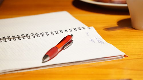 Close-up of pen and spiral notebook on wooden table