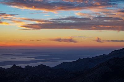 Scenic view of dramatic sky over silhouette mountains during sunset