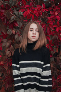 Portrait of young woman standing amidst plants