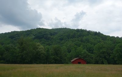 House on field by trees against sky