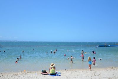 People enjoying at beach against sky
