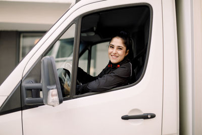 Confident young delivery woman driving truck