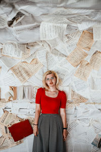 Portrait of woman against papers on wall