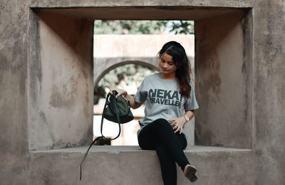 A woman wearing a gray t-shirt is sitting in an old building in the city of yogyakarta - indonesia.