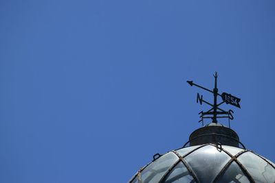 Low angle view of weather vane against blue sky