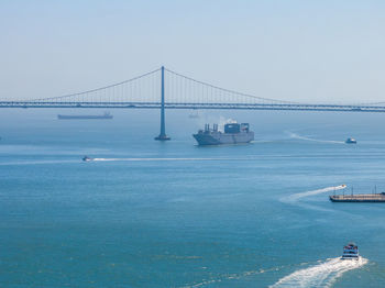 Suspension bridge over sea against clear sky