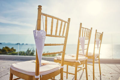 Close-up of chairs on table at beach against sky