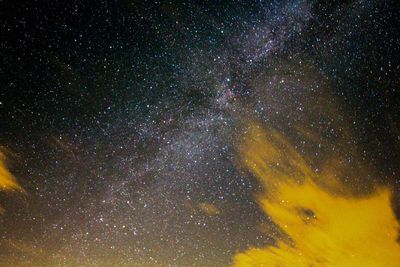 Low angle view of clouds against milky way during sunrise