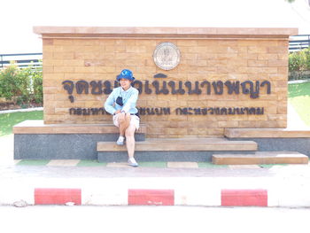 Full length portrait of woman standing against built structure