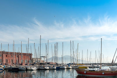 View of boats moored at harbor against cloudy sky