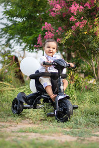 Portrait of boy riding push scooter on field