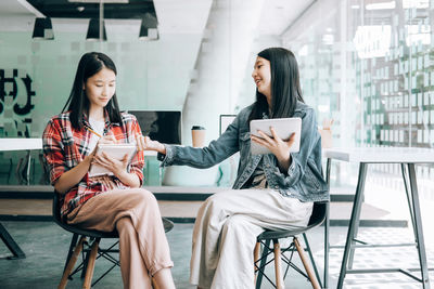 Young woman using phone while sitting on chair