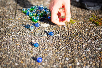 Cropped image of person playing with marbles on footpath