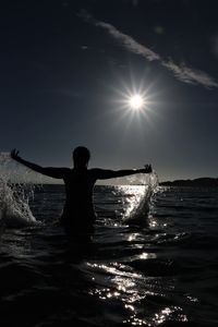 Silhouette man by sea against sky