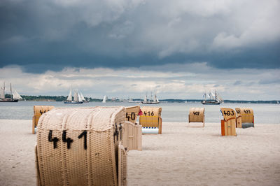 Hooded chairs on beach against sky