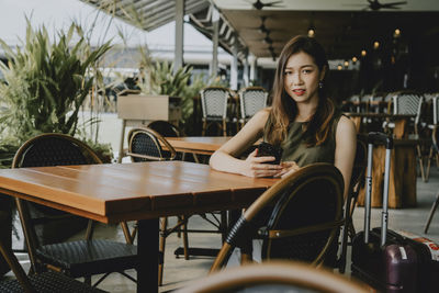 Portrait of woman sitting on chair at restaurant