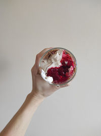 Close-up of hand holding ice cream against white background