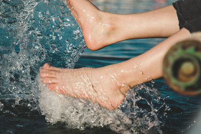 Low section of woman splashing water in lake