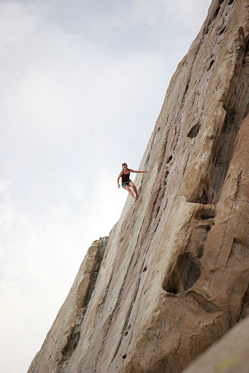 low angle view, leisure activity, lifestyles, sky, full length, men, climbing, adventure, mountain, rock - object, day, nature, clear sky, outdoors, extreme sports, risk, unrecognizable person