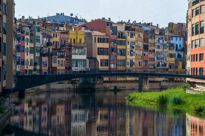 Buildings by river against sky in city
