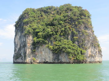 Scenic view of rocks by sea against sky