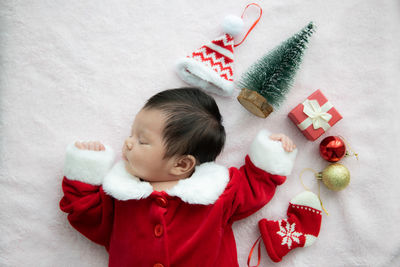 Directly above shot of baby girl wearing santa claus costume sleeping on bed at home