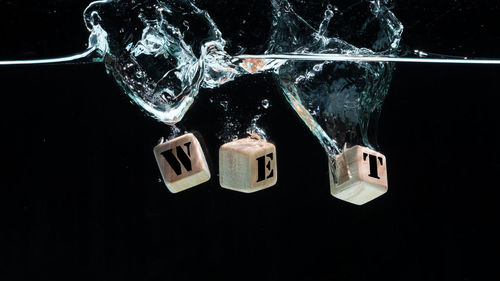 Close-up of glass over sea against black background