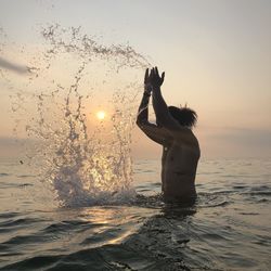 Man standing at beach against sky during sunset