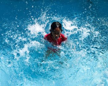 High angle view of child emerging from water in swimming pool