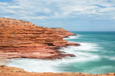 Rock formations on shore against sky