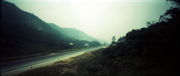 Road by mountains against sky