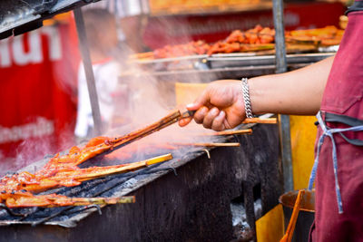 Person preparing food on barbecue grill