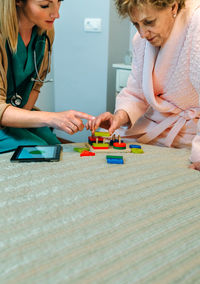 Nurse and senior patient playing with toys in hospital