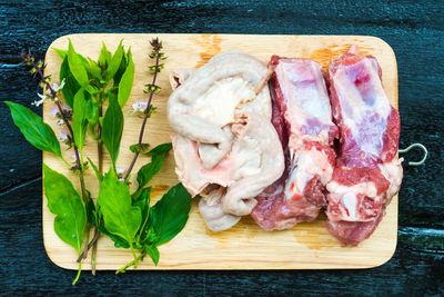 High angle view of meat and herbs on cutting board over table