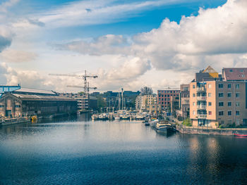 Buildings by river against sky in city