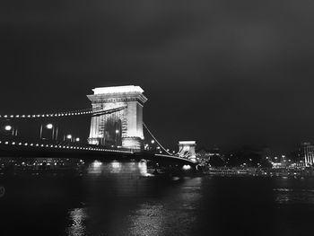 Illuminated bridge over water at night