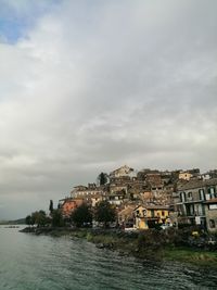 Buildings by sea against sky