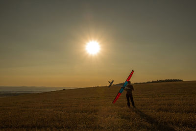 Man standing on field against sky during sunset