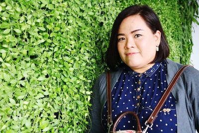 Portrait of beautiful woman standing against plants