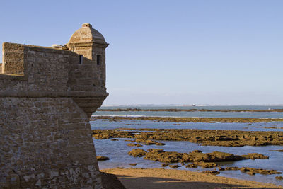 View of old building by sea against clear sky