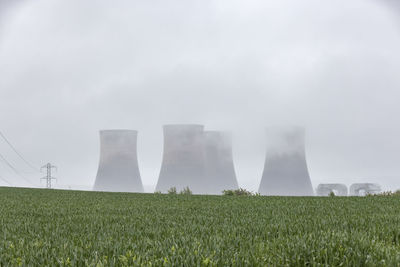 Uk, england, rugeley, large cooling towers during foggy weather with field in foreground