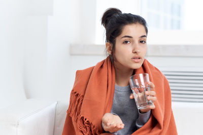 Portrait of sick woman holding medicine