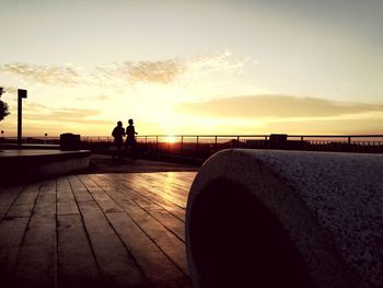 Silhouette man by sea against sky during sunset