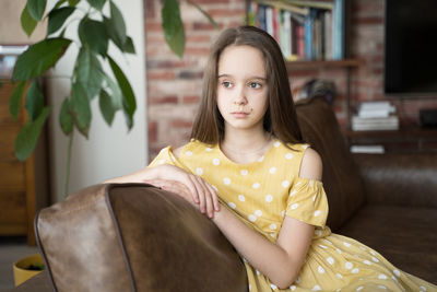 Frustrated thoughtful teen girl sitting on the couch in the living room