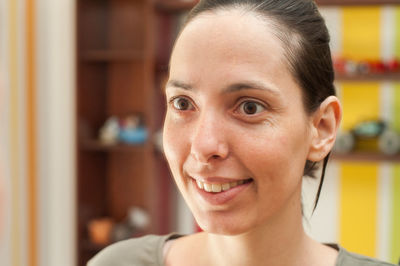 Close-up of smiling woman looking away at home