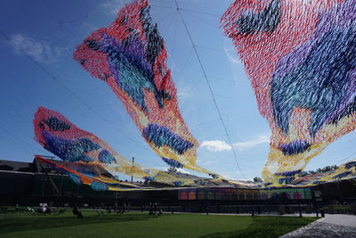 Low angle view of multi colored umbrellas hanging against sky