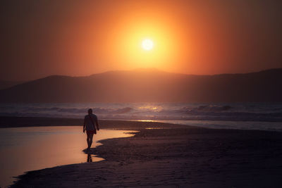 Silhouette woman on beach against sky during sunset