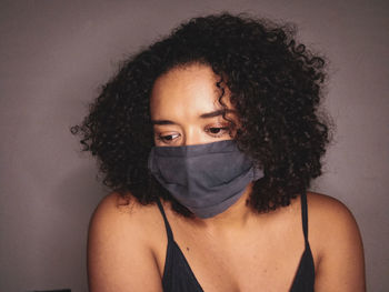 Portrait of young woman covering face against wall